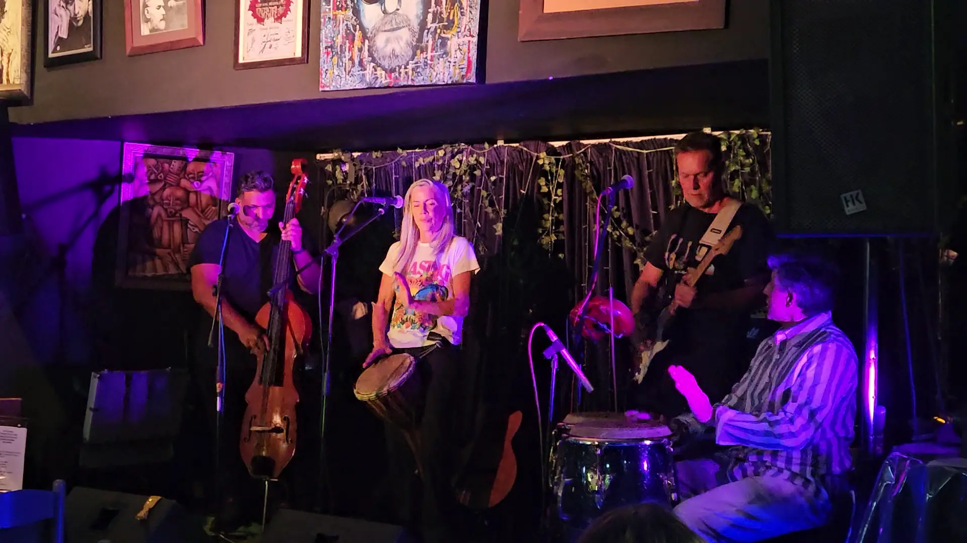 A band playing on the stage in purple light