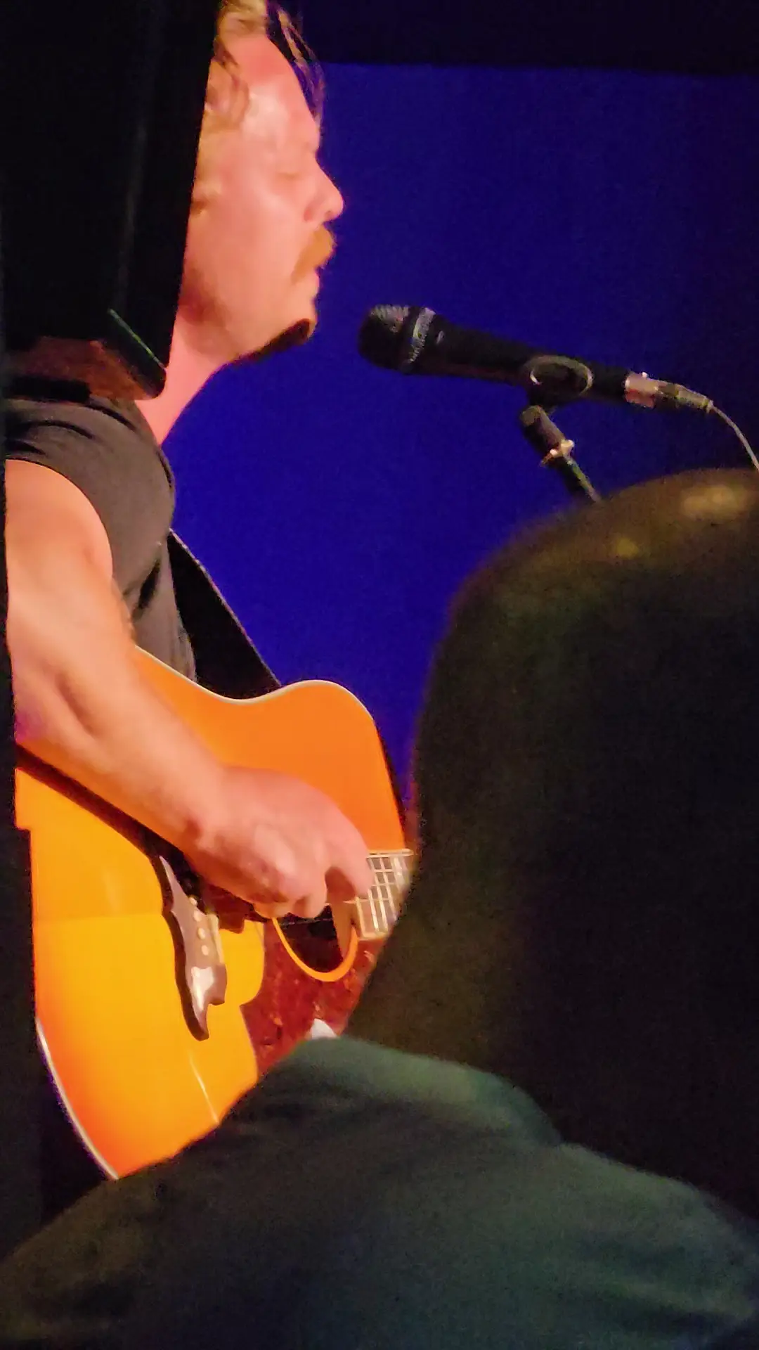 A singer with an acoustic guitar, up close
